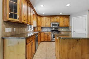 Kitchen featuring light tile patterned flooring, sink, tasteful backsplash, and stainless steel appliances