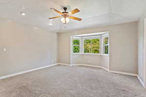 Spare room featuring carpet flooring, ceiling fan, and vaulted ceiling