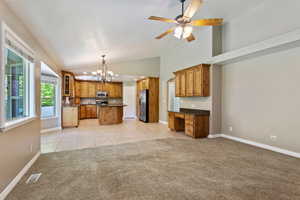 Kitchen with light colored carpet, decorative backsplash, stainless steel appliances, and an island with sink