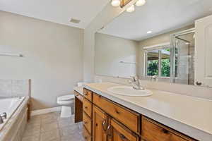 Full bathroom with vanity, toilet, separate shower and tub, and tile patterned flooring