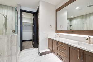 Bathroom featuring double vanity, walk in shower, and tile patterned floors