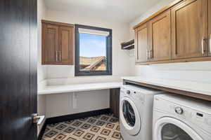 Clothes washing area with washing machine and clothes dryer, cabinets, and tile patterned floors