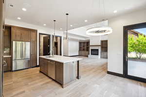 Kitchen featuring stainless steel appliances, pendant lighting, an island with sink, sink, and light hardwood / wood-style flooring