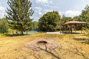 View of yard featuring a fire pit, pickle ball and or basketball court, a patio area, and a gazebo