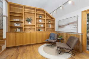 Living area featuring vaulted ceiling, rail lighting, light wood-type flooring, and a textured ceiling