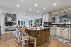 Kitchen featuring stone counters, a center island, light hardwood / wood-style flooring, and backsplash