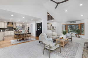 Living room featuring a towering ceiling, ceiling fan, and light colored carpet