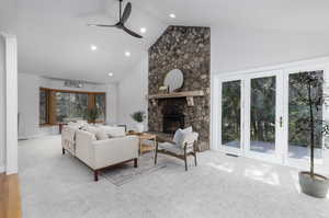 Living room with a fireplace, light carpet, ceiling fan, and a healthy amount of sunlight