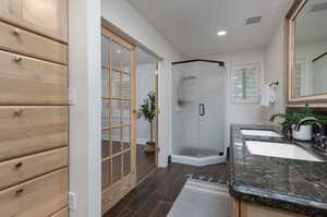 Bathroom with a shower with shower door, hardwood / wood-style floors, and dual bowl vanity