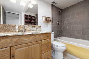 Full bathroom featuring vanity, tiled shower / bath combo, toilet, and tile patterned flooring