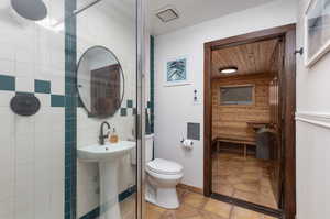 Bathroom featuring toilet, tile patterned flooring, and tile walls