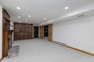 Unfurnished living room featuring a baseboard radiator and light carpet