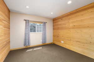 Carpeted spare room featuring wood walls