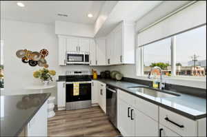 Kitchen featuring sink, dark hardwood / wood-style floors, appliances with stainless steel finishes, and white cabinets