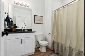 Bathroom featuring a shower with shower curtain, vanity, toilet, and hardwood / wood-style flooring