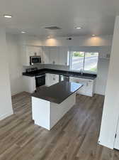 Kitchen featuring white cabinets, stainless steel appliances, wood-type flooring, and sink