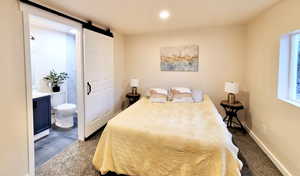 Tiled bedroom featuring ensuite bathroom, multiple windows, and a barn door