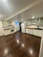 Kitchen featuring dark wood-type flooring, butcher block counters, white appliances, and sink