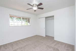 Unfurnished bedroom with a closet, ceiling fan, and light colored carpet