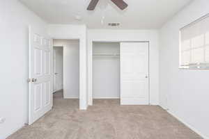 Unfurnished bedroom featuring a closet, ceiling fan, and light colored carpet