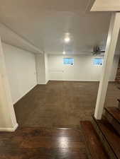 Basement with a textured ceiling, dark carpet, and ceiling fan