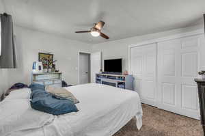 Bedroom with light carpet, a closet, and ceiling fan