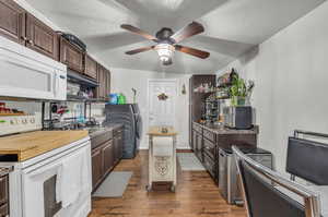 Kitchen featuring hardwood / wood-style flooring, white appliances, dark brown cabinets, a textured ceiling, and ceiling fan