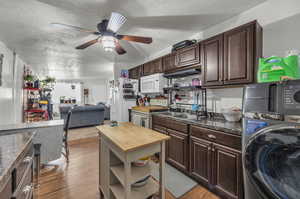 Kitchen featuring dark brown cabinets, light hardwood / wood-style flooring, stacked washer and dryer, and white appliances