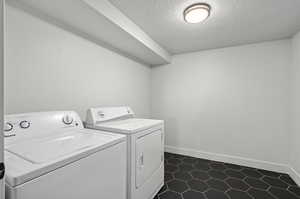 Clothes washing area featuring tile patterned flooring, separate washer and dryer.