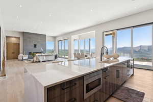 Kitchen with modern cabinets, stainless steel microwave, a large island with sink, light wood-style floors, and recessed lighting