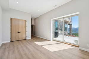 Unfurnished bedroom featuring access to exterior, light wood-type flooring, a mountain view, and recessed lighting