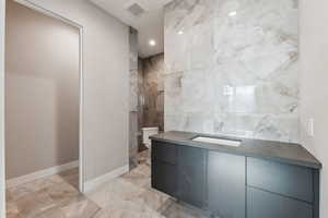 Bathroom featuring visible vents, baseboards, toilet, marble finish floor, and vanity