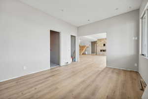 Spare room featuring light wood-type flooring, a fireplace, and a wealth of natural light