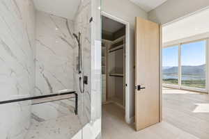 Full bath with a marble finish shower, a walk in closet, and a water and mountain view
