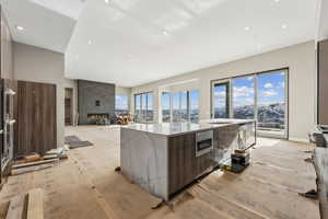 Kitchen with light wood-style flooring, light stone countertops, modern cabinets, and a large island with sink