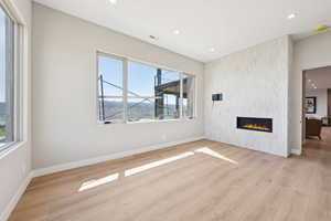Unfurnished living room with light wood-style flooring, recessed lighting, and a large fireplace
