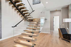 Staircase with wood finished floors and recessed lighting