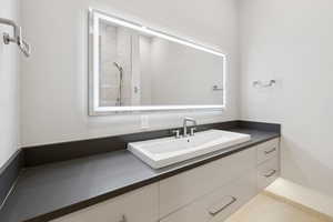 Bathroom with vanity, tiled shower, and tile patterned flooring
