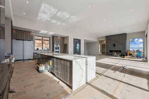 Kitchen featuring light stone counters, refrigerator, recessed lighting, a large island, and modern cabinets