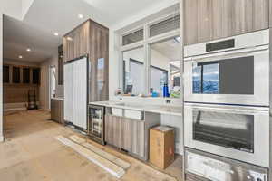 Kitchen featuring beverage cooler, recessed lighting, double oven, a warming drawer, and modern cabinets