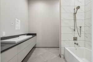 Bathroom with tub / shower combination, vanity, and baseboards