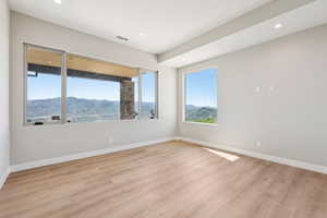 Spare room featuring light wood-style flooring, a mountain view, and recessed lighting