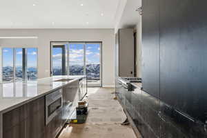 Kitchen featuring light stone counters, light wood finished floors, stainless steel gas stovetop, wall oven, and modern cabinets