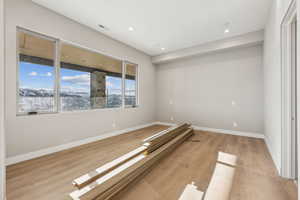 Empty room with recessed lighting, visible vents, baseboards, and light wood-style floors