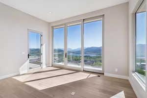 Empty room with a mountain view, wood finished floors, and healthy amount of natural light
