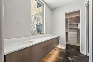 Bathroom featuring baseboards, vanity, marble finish floor, and a spacious closet