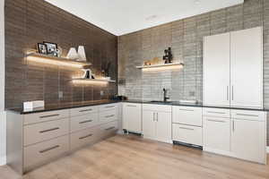 Kitchen featuring open shelves, decorative backsplash, dark countertops, light wood finished floors, and white cabinets