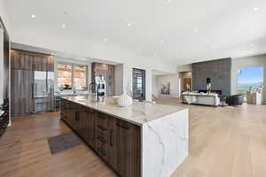 Kitchen with modern cabinets, a large island with sink, light wood-style floors, plenty of natural light, and recessed lighting