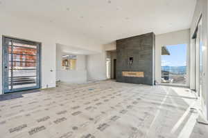 Unfurnished living room featuring a tiled fireplace, a mountain view, plenty of natural light, and tile walls