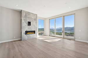 Unfurnished living room featuring a mountain view, wood finished floors, a high end fireplace, and recessed lighting
